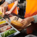 Closeup image of food truck worker putting pork floss in cut wheat bun